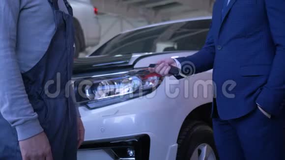 男性客户将汽车钥匙交给汽车修理工修理并在服务时与汽车背景握手视频的预览图