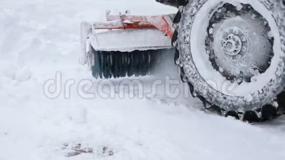 一辆拖拉机的特写用大刷子扫雪从城市的街道视频的预览图