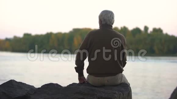 一个悲伤的人坐在河畔想着他生命中的时刻怀念视频的预览图