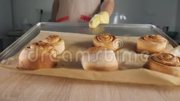 糕点厨师把刚烤好的肉桂卷从烤盘放在桌子上视频的预览图
