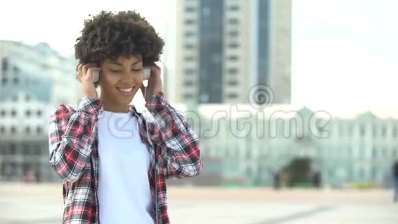 年轻的卷发女子用耳机听音乐唱歌视频的预览图