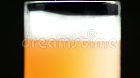 极端近距离工艺啤酒与蓬松泡沫和气泡在透明杯隔离旋转视频的预览图