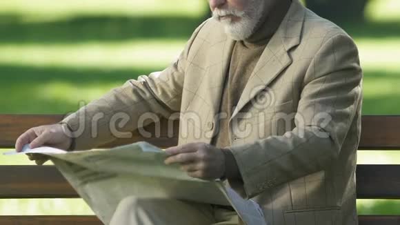 白发苍苍的退休老人在早晨的公园里拿着报纸休息退休仪式视频的预览图
