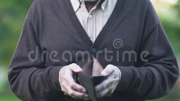 悲伤的退休男子在镜头前拿出空钱包可怜的养老金支付视频的预览图