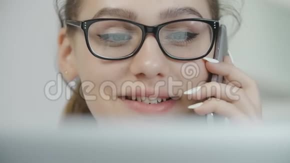 十几岁的女孩讲手机用笔记本电脑和微笑有魅力的女人带着智能手机视频的预览图