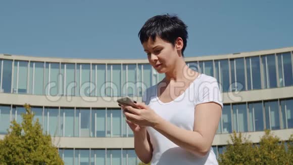 商务女性坐在一栋办公楼前在电话里留言视频的预览图