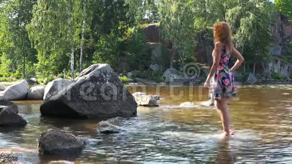 一个女孩赤脚站在水里的石头上视频的预览图