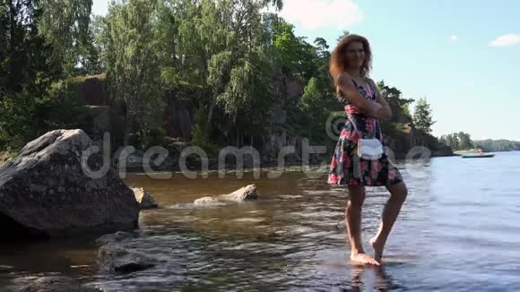 一个头发红的女孩在夏天的阳光下双脚在水里视频的预览图