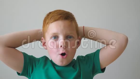 英俊的红发男孩长着雀斑看着镜头举起双手内心充满喜悦的成就肖像视频的预览图