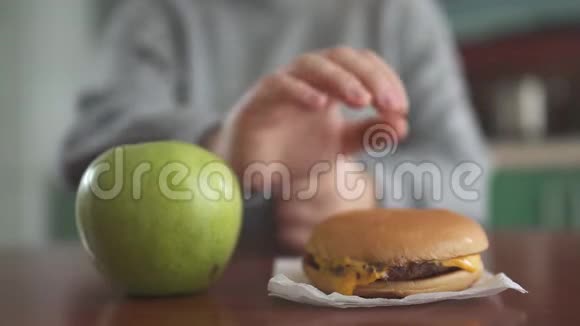 靠近苹果和汉堡躺在模糊的身影面前的胖乎乎的女孩女人的手想带走视频的预览图
