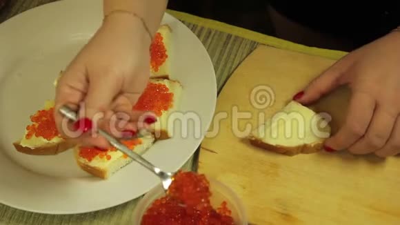 一位女士用黄油和红色鱼子酱涂抹罐头作为自助餐桌视频的预览图