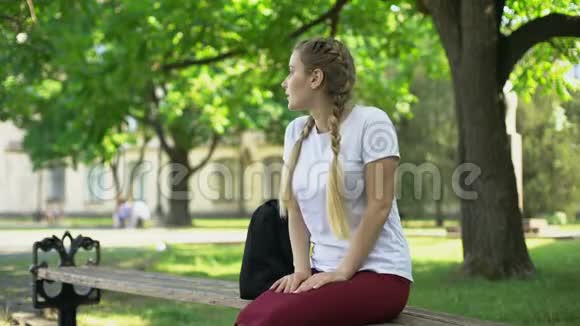 年轻的女士等着朋友坐在长凳上没人来就走开了视频的预览图