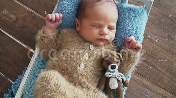 新生婴儿穿着棕色服装睡在照片区视频的预览图