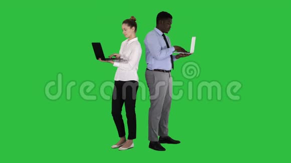 两个背靠背站着在绿色屏幕上的笔记本电脑上工作Chroma键视频的预览图