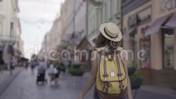 镜头跟随年轻女子背着背包走在拥挤的小街道上有着令人惊叹的建筑拥有伟大的视频的预览图