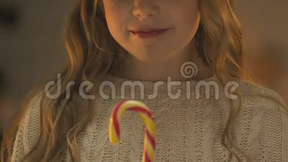 快乐的女孩吃甘蔗糖在圣诞节享受焦糖糖果特写视频的预览图