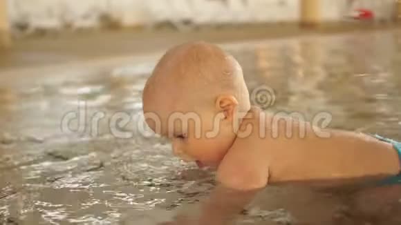 儿童泳池里一个孩子肖像一个孩子看着路过的人滚到他身边视频的预览图