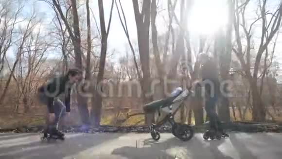 家庭幸福年轻的父母和一个孩子在城市公园的婴儿车里轮滑秋天晴天空气清新爸爸视频的预览图