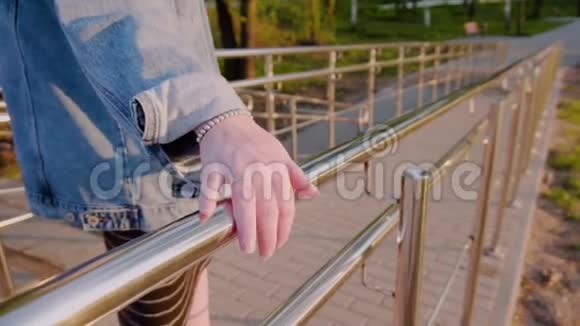 女孩穿过城市牵着他的手在金属扶手上很漂亮的计划特写少女的手去吧视频的预览图