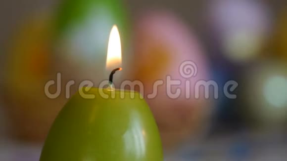 用复活节彩蛋做成的蜡烛燃烧蜡烛绿色橙色黄色滑动特写视频的预览图