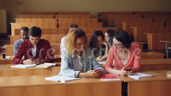 快乐的学生在大学期间使用智能手机和聊天现代技术视频的预览图