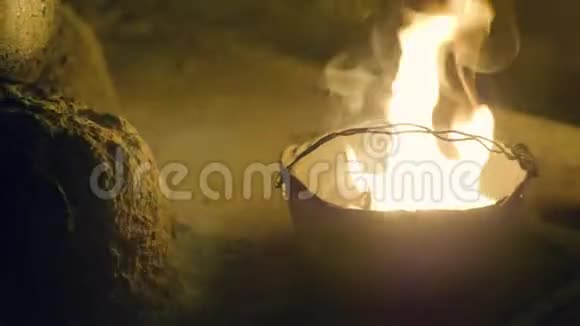 在黑暗的晚上在保龄球锅里燃烧火焰夜间露营时游客用水壶烧火视频的预览图