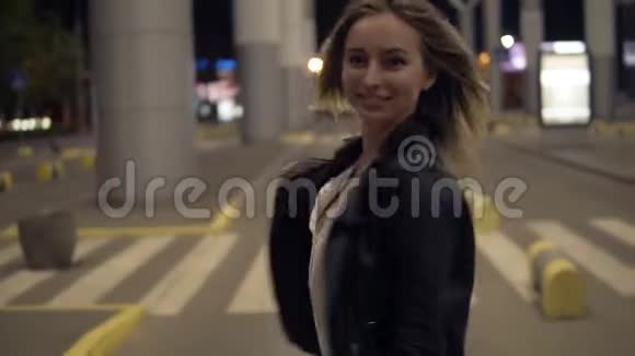 在城市的一条空路旁散步的美丽年轻女子的正面景色金发女孩微笑摆姿势拍照视频的预览图
