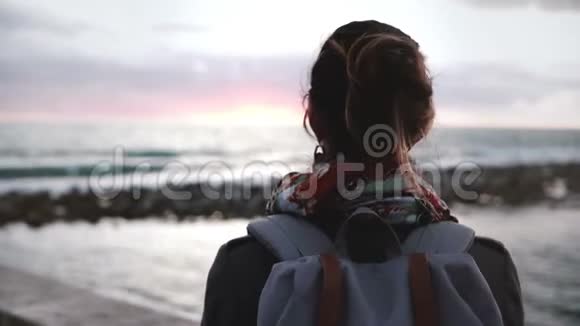 特写后景拍摄的女孩背包看日落在美丽的海岸享受美丽的生活时刻视频的预览图