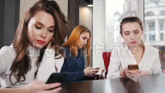 三个年轻漂亮的女人在胡克的地方默默地坐在电话前视频的预览图