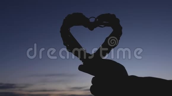 恋爱中的女孩在日落时用手捧着心浪漫的蜜月情人节特写视频的预览图