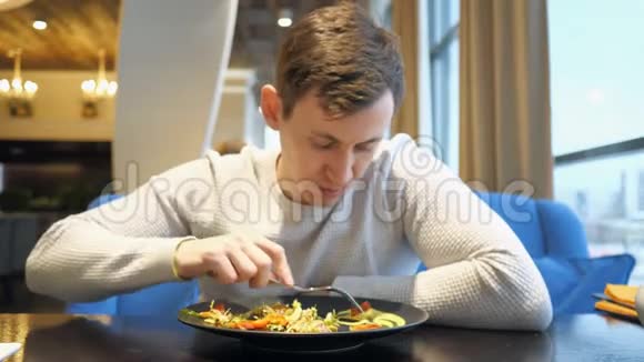 有魅力的男人坐在咖啡馆里吃沙拉视频的预览图