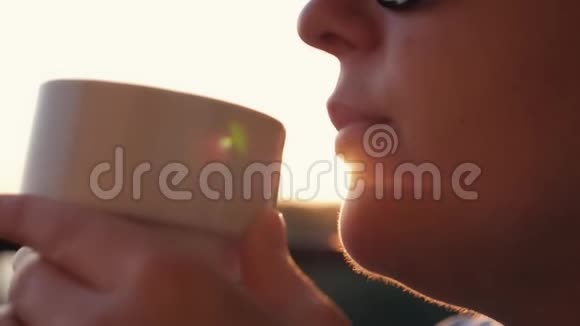 女人在阳光下喝咖啡在阳光下户外享受她的早晨咖啡视频的预览图