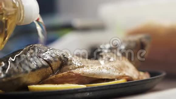 新鲜的鲭鱼撒上香料加入柠檬在黑色盘子里倒入葵花籽油模糊的视频的预览图
