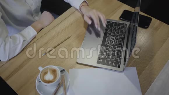 在咖啡馆或餐馆里使用笔记本电脑的女人的俯视图头顶射中坐在桌子旁端着杯子的年轻女子视频的预览图