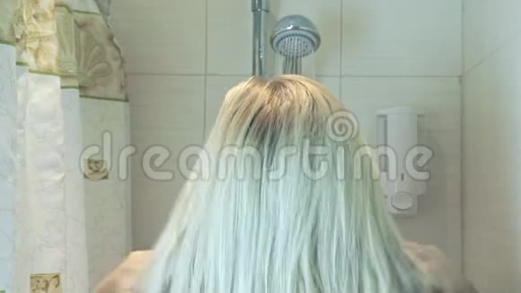金发女人摸她的头发水从浴室的淋浴头掉下来用水弄湿她的头发身体护理概念视频的预览图