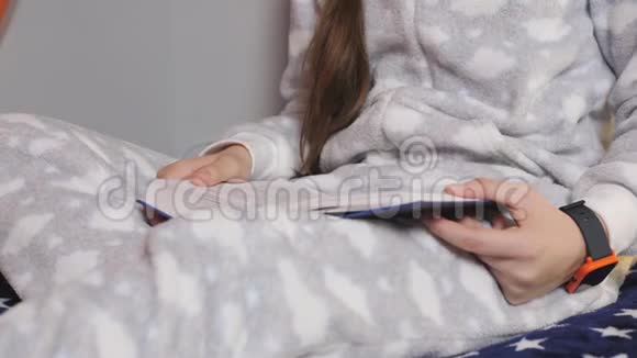 那个女孩少年穿着温暖的睡衣坐在床上看书特写视频的预览图