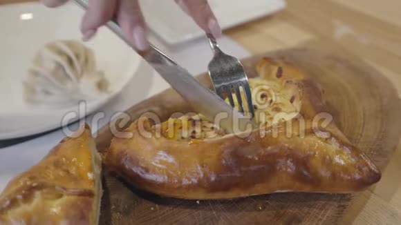 女人用叉子和刀子切馅饼咖啡屋的木板上放着鸡蛋和奶酪视频的预览图