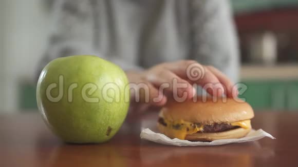 不认识的女孩认为她应该吃美味的汉堡包或多汁的绿色苹果健康的选择视频的预览图