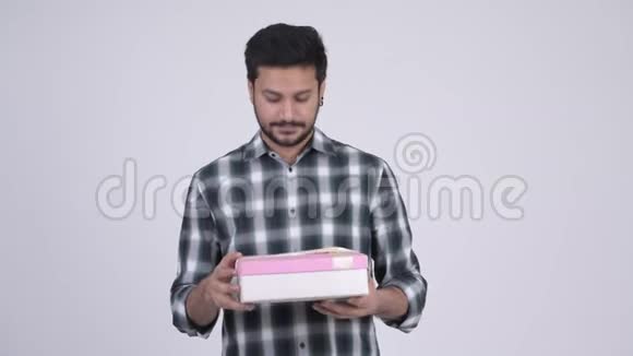 年轻快乐留胡子的印度男人打开礼品盒视频的预览图