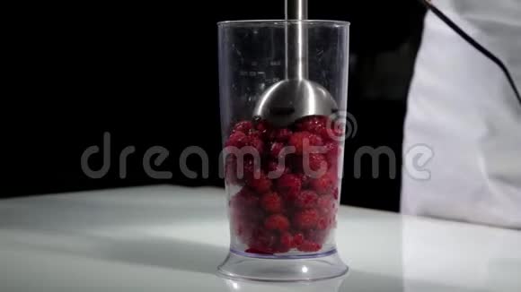 女人做健康的早餐把覆盆子混合到搅拌机里做水果鸡尾酒视频的预览图