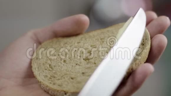 男人手慢慢地在厨房的面包上铺上黄油作为早餐视频的预览图