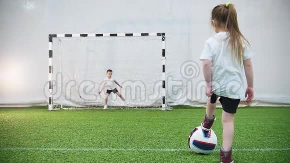 小孩子在踢足球一个小女孩踢球但看门人保护大门视频的预览图