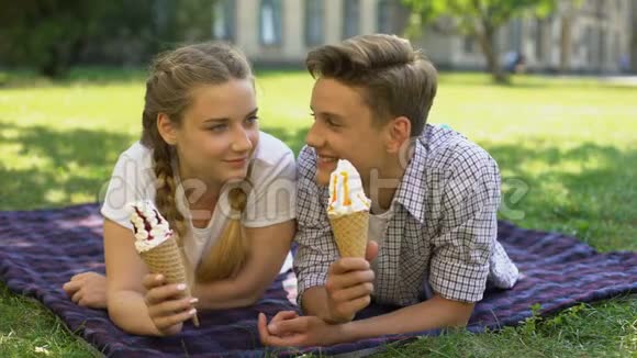 有趣的青少年用冰淇淋互相喂饭躺在格子布上到处胡闹视频的预览图