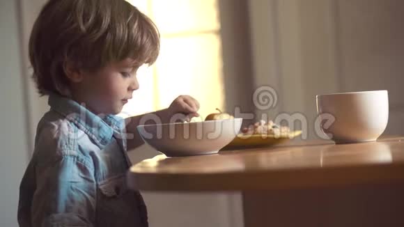 美丽的孩子在家吃早餐的肖像厨房里的孩子在桌子旁吃饭嘲笑可爱的孩子视频的预览图
