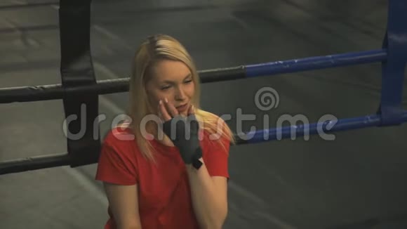 训练结束后美丽疲惫的金发女郎坐在拳击台上视频的预览图