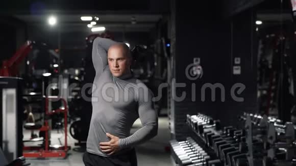 强壮的肌肉男用哑铃做运动锻炼在黑暗的健身房训练三头肌手部肌肉A视频的预览图