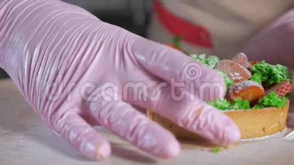 橡胶手套中的糕点厨师显示了在一半草莓迷你蛋糕中切割的填充视频的预览图