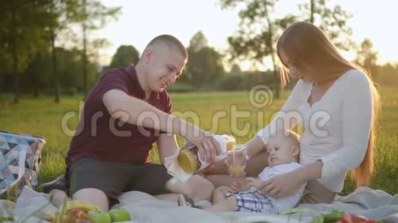 可爱的家人在第一次野餐时倒果汁视频的预览图