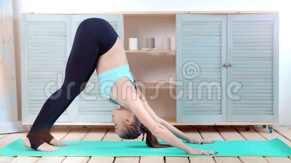 年轻的运动女性在木地板工作室的垫子上做瑜伽视频的预览图