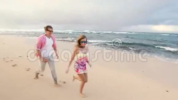 有魅力的健康夫妇在海滩上一起跑步很开心视频的预览图